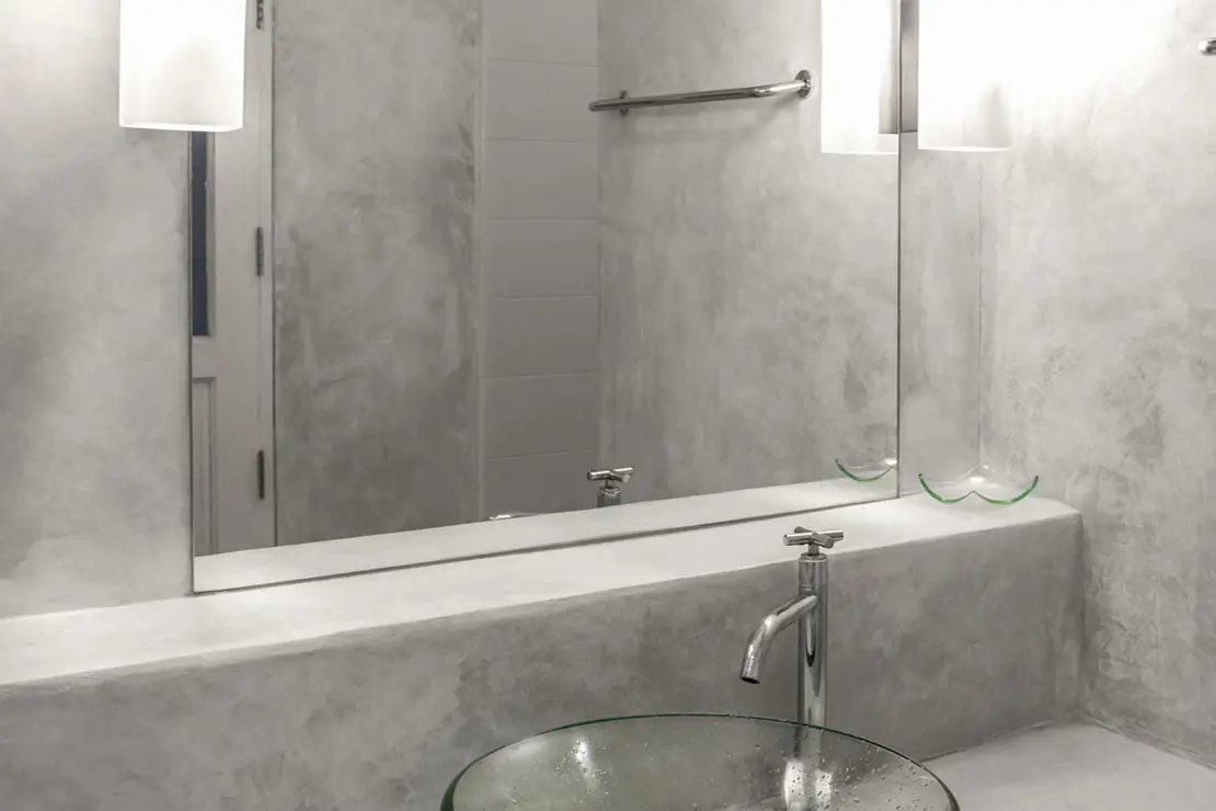Cuarto de baño con muros y superficie de microcemento de color gris.